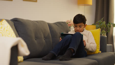 Young-Boy-Sitting-On-Sofa-At-Home-Playing-Games-Or-Streaming-Onto-Digital-Tablet-5